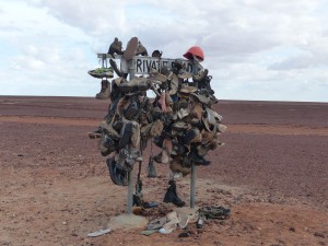 A signpost adorned with pairs of shoes... And a hat